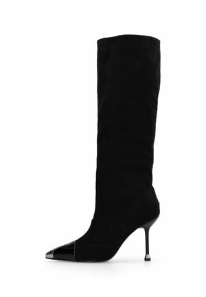 Botte noire en daim montant jusqu'au genou avec un talon aiguilles, un bout pointu et un détail brillant noir sur le bout.