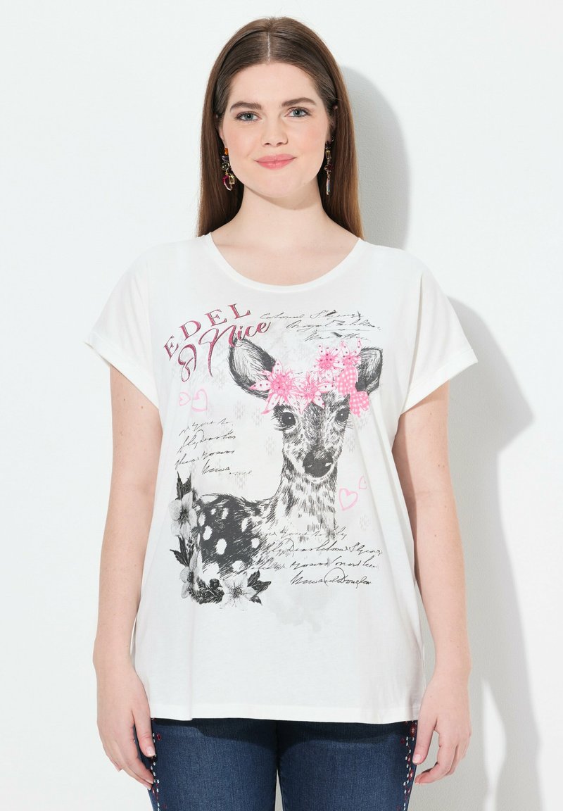 Camiseta blanca de manga corta con un gráfico de un ciervo rodeado de flores y texto. Tela suave, corte relajado y escote redondo.