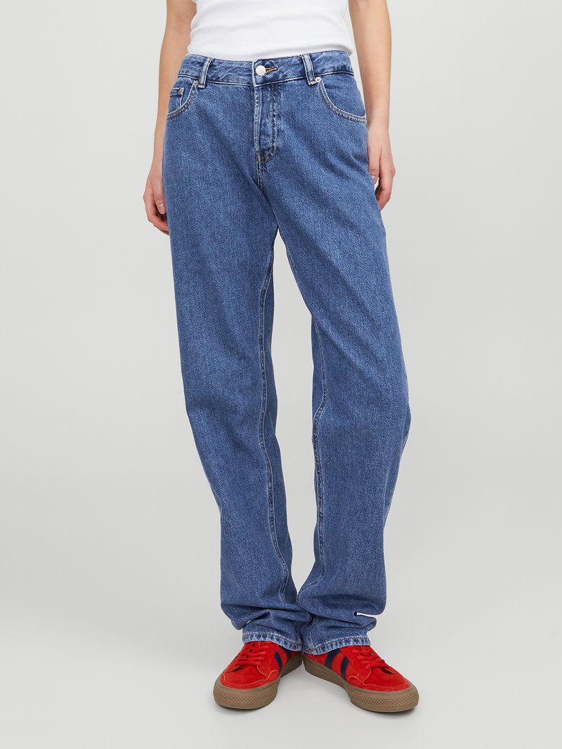 Calças de ganga azul claro com um design de perna reta, cinco bolsos e detalhes de costura sutis, combinadas com ténis vermelhos.