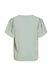 Svijetlo zelena bluzica s napuhanim kratkim rukavima i okruglim izrezom. Glatka tekstura s nabranim detaljima na prošivima ramena.