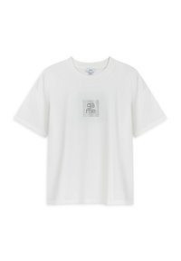 Camiseta de algodón blanca con un corte relajado. Presenta un gráfico cuadrado con la palabra "juego" en strass negros en el pecho. Mangas cortas.