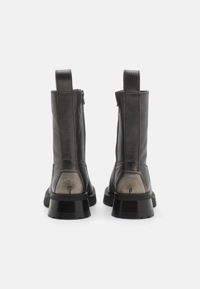 Stivaletti neri in pelle con finitura testurizzata, zip posteriore e tacco grigio chiaro a contrasto. Linguette verticali su entrambi i lati.