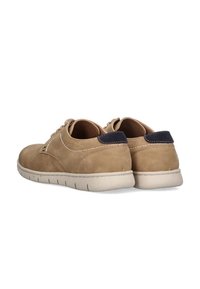 Zapatos de ante beige con una superficie texturizada, puntera redonda y detalle en el tacón azul marino en contraste. Cuentan con una suela de goma blanca y cierre de cordones.
