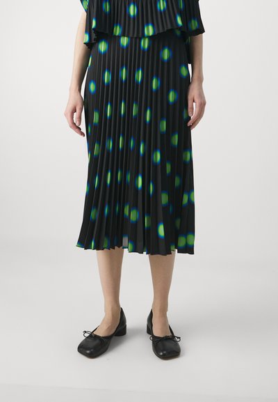 Black pleated skirt with large blue and green polka dots, paired with black flats featuring bows. Smooth, lightweight fabric.