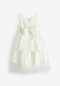 Robe blanche en tissu lisse avec une superposition en tulle. Présente un décolleté en V, un devant à boutons, un large nœud en satin à la taille et une coupe sans manches.