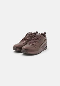 Brown leather athletic shoes with textured detailing, lace closure, padded collar, and visible air cushioning in the sole.