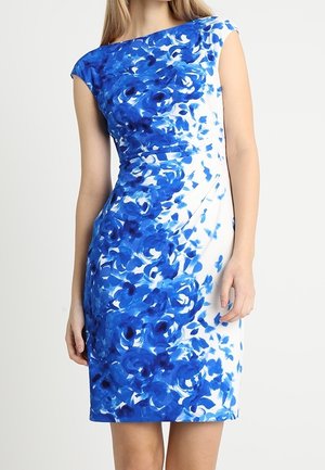 Biała sukienka bez rękawów z niebieskim kwiatowym wzorem, dopasowaną talią i łódkowym dekoltem, noszona przez stojącą osobę na jednolitym tle.