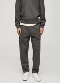 Szary sweatshirt i dopasowane spodnie z miękkiego materiału, charakteryzujące się luźnym krojem, ściągaczami przy mankietach i bocznymi kieszeniami. Całość dopełniają białe sneakersy.