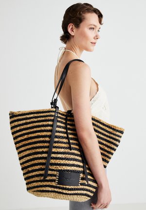 Bolso tote de fibra trenzada a rayas en negro y marrón con asas de cuero y una etiqueta de parche. Diseño espacioso con un acabado texturizado.