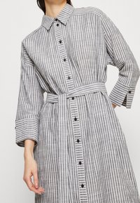 Gestreiftes Hemdkleid in Grau und Weiß, mit Kragen, knöpfbarem Vorderteil und Taillengürtel, breiten Ärmeln und strukturierter Stoffqualität.