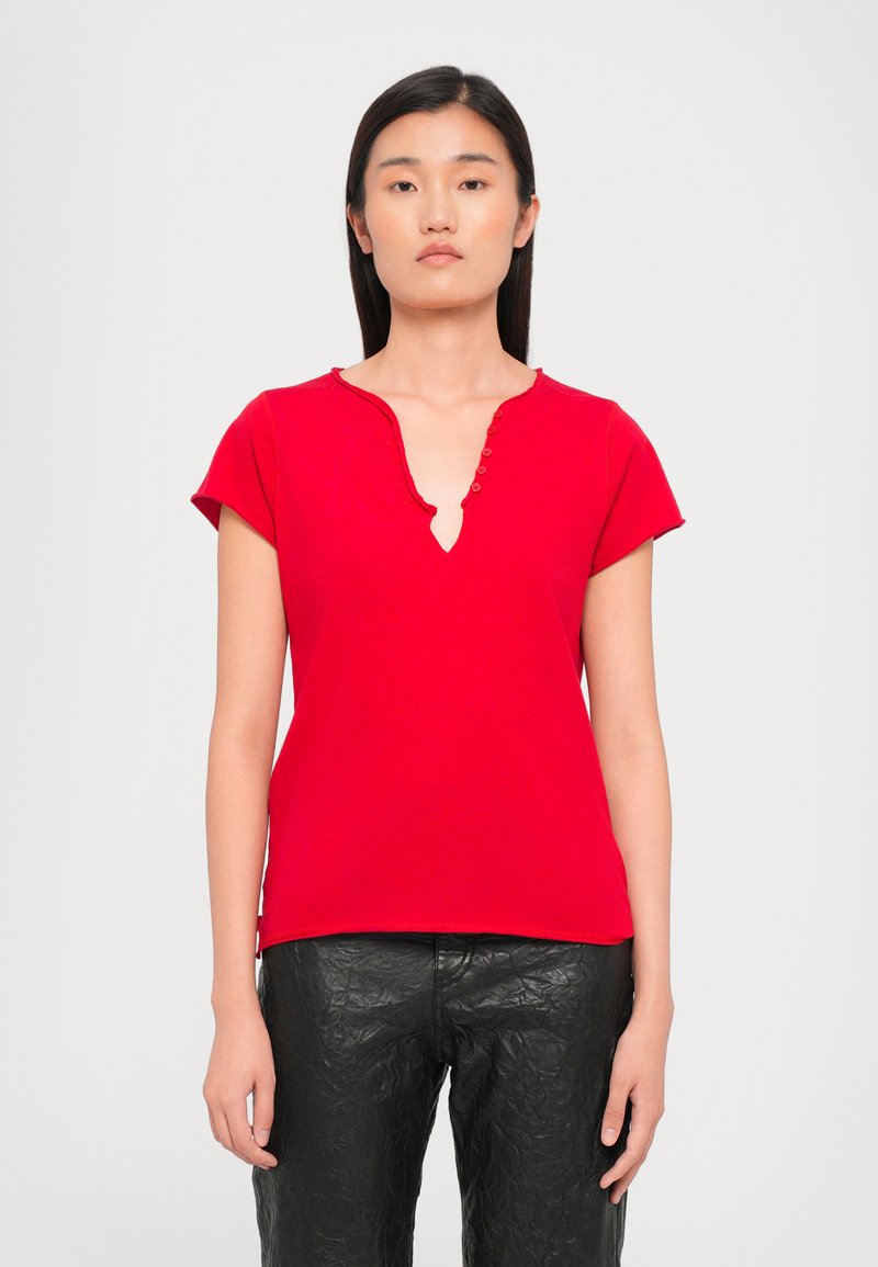 Red short-sleeve top with a V-neckline, featuring a row of decorative buttons along the collar. Made from smooth, lightweight fabric.