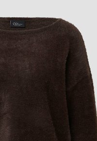 Brązowy puszysty sweter z okrągłym dekoltem i długimi rękawami. Materiał wygląda na miękki i teksturowany, z subtelnym połyskiem i bez widocznych wzorów.