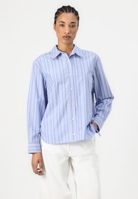 Blue and white striped button-up shirt with a classic collar, long sleeves, and side ties, made from a lightweight fabric.