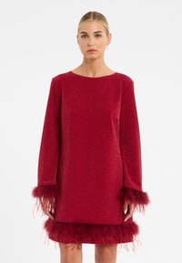 Rotes Glitzerkleid mit langen Ärmeln, verziert mit Federakzenten an den Bündchen und dem Saum. Glatte Textur mit lockerer Passform und rundem Ausschnitt.