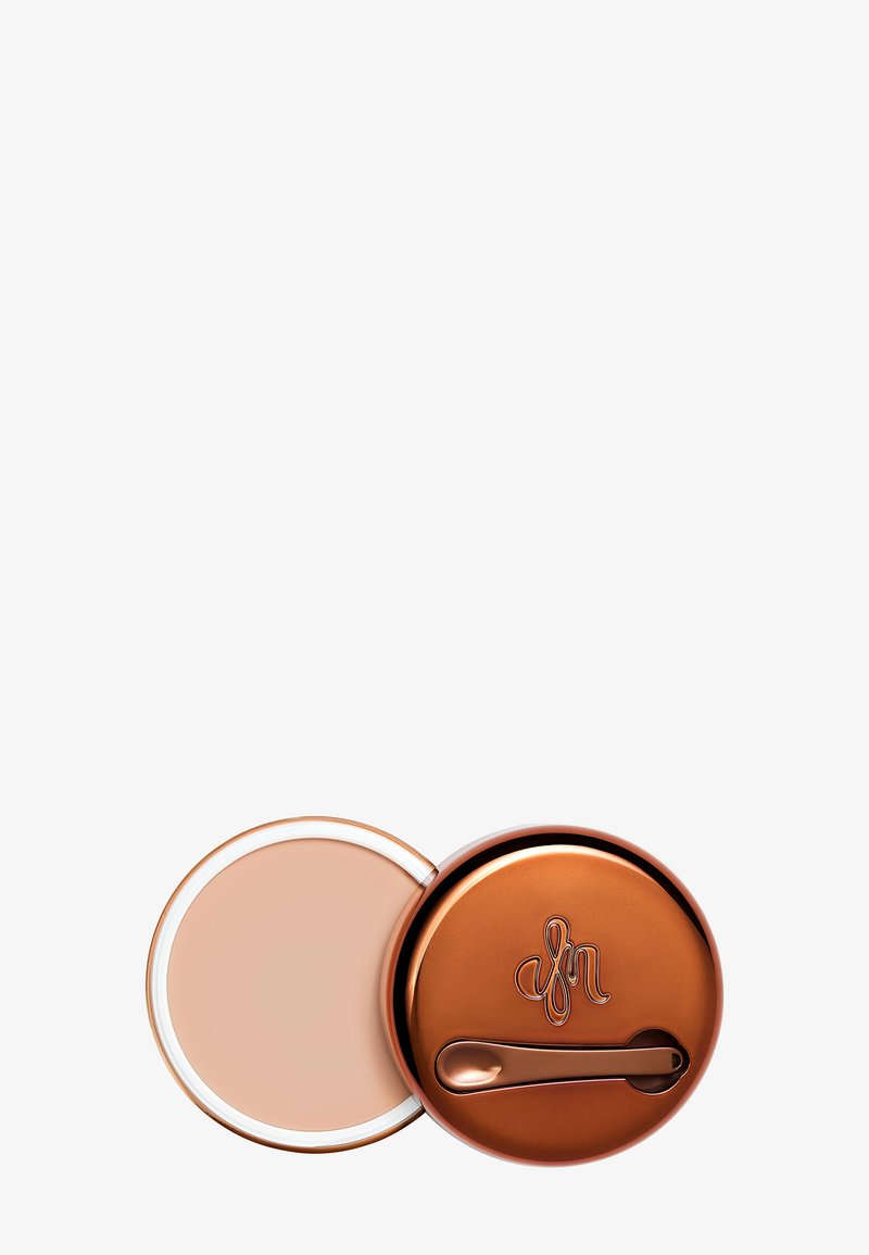 Kompaktpuder med ett bronsfärgat metallock som har en logotyp. Den inre behållaren är ljusbeige och rund, med en slät yta.