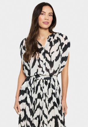 Black and white patterned dress with a high neckline, short sleeves, and a button detail at the chest. Flowing pleated skirt design.