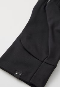 Svarte treninghansker laget av glatt, elastisk stoff med en tettsittende design. Har en liten hvit Nike-logo ved mansjetten.