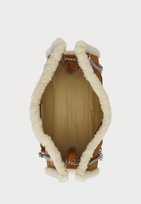 Barna szarvasbőr kézitáska krém színű műszőrme díszítéssel, fémből készült lánc részletekkel és jól meghatározott formával; belsejében bézs színű bélés található.