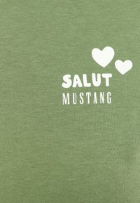 Green cotton fabric featuring white text "SALUT MUSTANG" with two heart shapes. Smooth texture, casual design.
