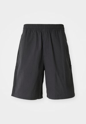 Fekete térdnél rövidebb, texturált, bordázott dizájnnal készült rövidnadrág, gumírozott derékpánttal és két oldalsó zsebbel. Lazább stílusú.