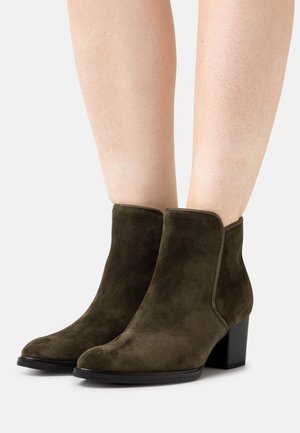 Suede ankle boots in dark olive green with a rounded toe, side stitching, and a low block heel. Smooth texture and sleek design.