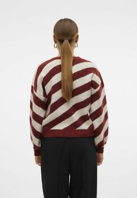 Maglione lavorato a maglia con righe diagonali rosse e bianche, vestibilità comoda, collo rotondo e polsini e orlo a coste. Texture liscia e morbida.