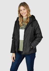 Schwarze isolierte Jacke mit Kapuze, mit einem Reißverschluss vorne, Druckknöpfen und Seitentaschen. Getragen über einem grün-weißen gemusterten Sweater.
