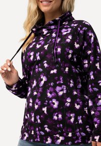 Felpa nera con motivo floreale in viola e bianco, collo a cowl con cordini, maniche lunghe e vestibilità rilassata. Tessuto morbido e strutturato.