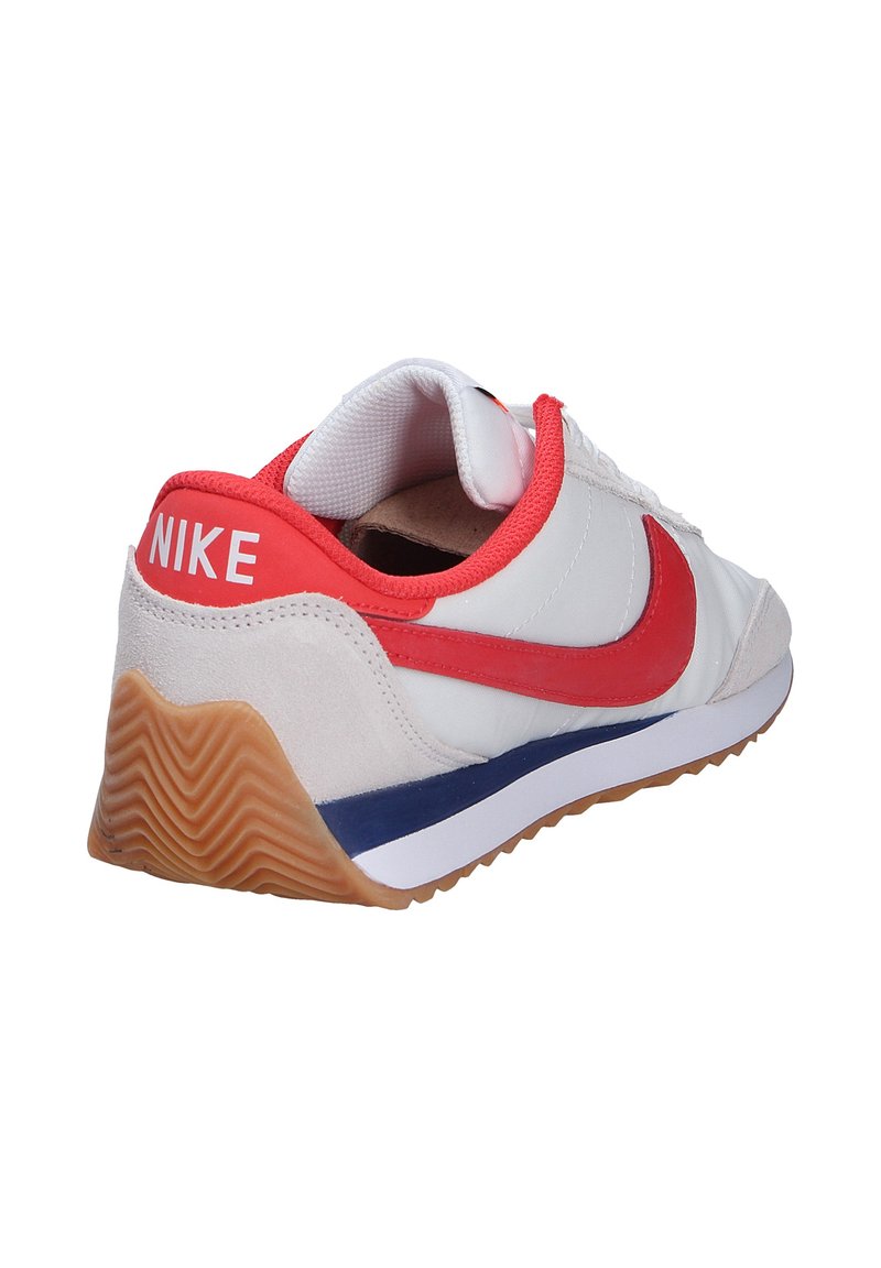 Zapatilla blanca con acentos rojos y un logo rojo, que presenta un panel texturizado blanco y gris, suela de goma y un diseño curvado.