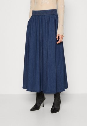 Jeans-Maxi-Rock mit einem gerafften Gummibund, dunkelblauer Farbe und seitlichen Taschen, kombiniert mit schwarzen spitzen Ankle Boots.