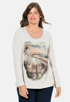 Helles beige Langarmshirt mit rundem Ausschnitt. Verfügt über ein bedrucktes Küstenszenario in sanften Pastellfarben. Strukturierter Stoff mit einem Etikett am Saum.