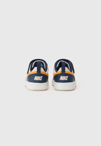 Baskets Nike en bleu marine et blanc, avec une touche d'orange, en cuir texturé et dotées d'un talon rembourré pour plus de confort.