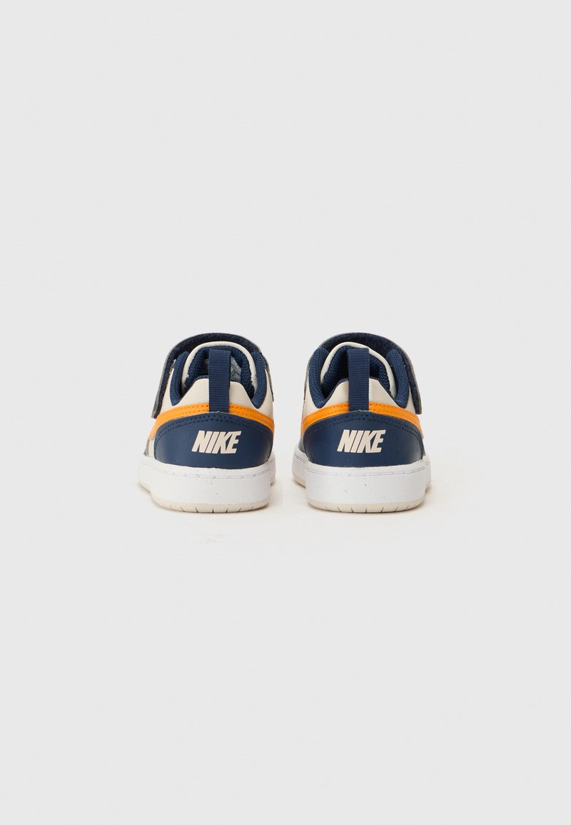 Sneakers Nike w granatowo-białym kolorze, z pomarańczowym akcentem, wykonane z teksturowanej skóry oraz z wyściełanym zapiętkiem dla komfortu.