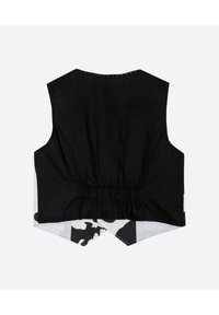 Svart ärmlös topp med mesh-textur och rynkad rygg, med ett vitt och svart mönstrat underlager och spetsig nederkant bak.