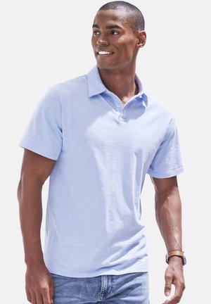Helles blaues Poloshirt mit kurzen Ärmeln und Kragen, das eine subtile Textur und eine Dreiknopf-Leiste aufweist, kombiniert mit Jeans aus Denim.