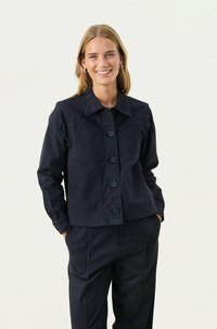 Námornícky modrá, zapínacia bunda vyrobená z bavlny, s dvoma prednými vreckami, golierom a dlhými rukávmi s uvoľneným strihom.