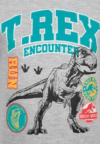T. Rex-Illustration mit Dinosaurierfußabdrücken, Text "T. REX ENCOUNTER" und Jurassic World-Logos auf einem grauen Hintergrund.
