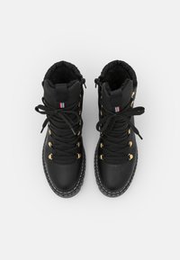 Botas de senderismo negras con un acabado texturizado, ojales dorados y cordones negros. Cuenta con un collar acolchado y una lengüeta en la parte posterior.