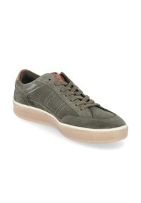 Zapatilla informal de ante verde oliva con suela de goma beige, cierre de cordones y un detalle de cuero marrón en el talón y la lengüeta.