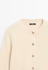 Light beige cardigan made of soft material, featuring a ribbed collar, and five round, metallic buttons at the front.