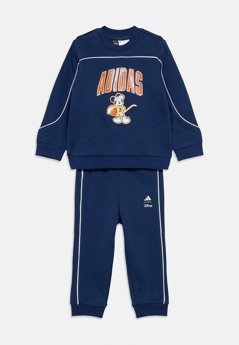 Set trening bleumarin format din bluză sport cu un grafic Mickey Mouse și textul "ADIDAS"; include pantaloni asortați cu accente albe și logo.