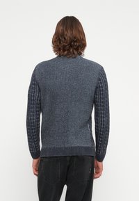 Gebreide trui in verschillende tinten blauw, met een textuurpatroon op de mouwen, een ronde hals en geribde onderrand en manchetten.