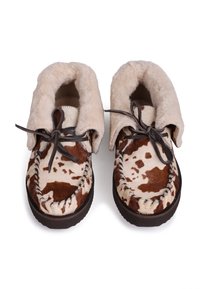 Chaussures de style mocassin marron et crème avec une doublure en fourrure, des lacets en cuir et un extérieur à motif ressemblant à des imprimés animaliers. Semelle plate en caoutchouc.