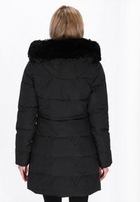 Cappotto puffo nero con colletto in pelliccia sintetica, caratterizzato da un design trapuntato e un cappuccio. Il cappotto ha maniche lunghe e una vita aderente.