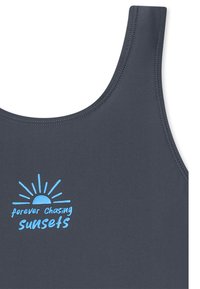 Graues Tanktop mit runder Ausschnittlinie, das blauen Text "forever chasing sunsets" und eine Sonnen-Grafik zeigt. Glatte Textur und genähte Details.