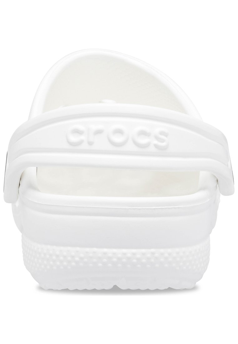 White Crocs clogs with a textured surface, adjustable heel strap, and logo detail. Features a lightweight, flexible design and cushioned footbed.