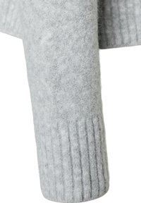 Hellgrauer Wollpulloverärmel mit weicher Textur und gerippten Details am Bündchen für zusätzliche Struktur und Stil.