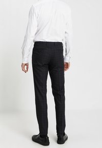 Slim-fit, marinblå rutiga byxor med en slät textur, två bakfickor och en flat frontdesign. Matchas med svarta skor och en vit skjorta.