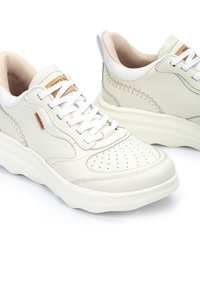 Zapatillas de cuero blancas con puntera perforada, costuras en contraste y un interior beige. Con cordones blancos y un cuello acolchado para mayor comodidad.