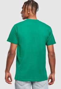 Camiseta de algodón verde con cuello redondo y mangas cortas, que presenta una textura suave y un ajuste relajado, vista desde la parte posterior.